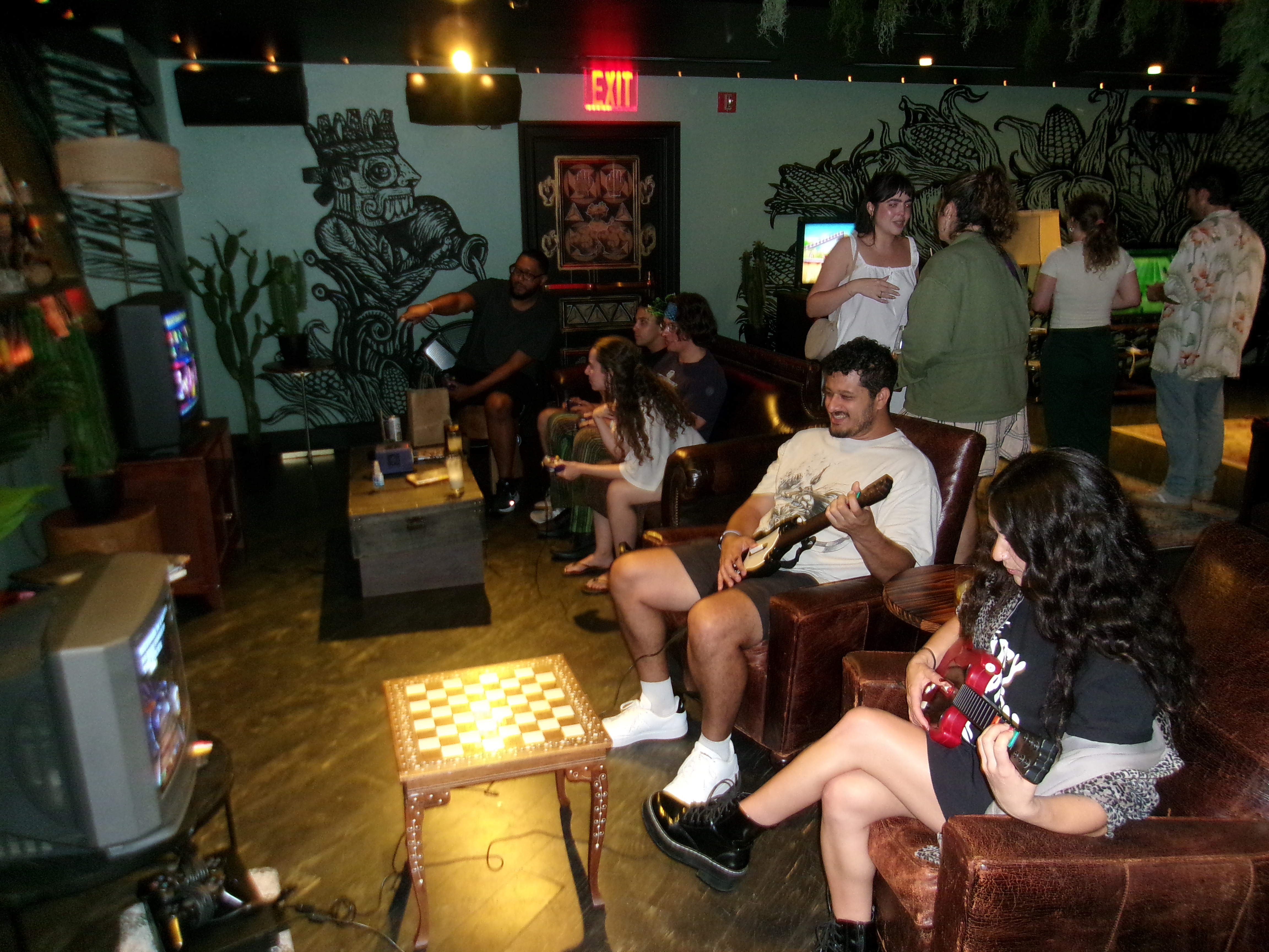 Friends playing Guitar Hero and hanging out across a cozy room