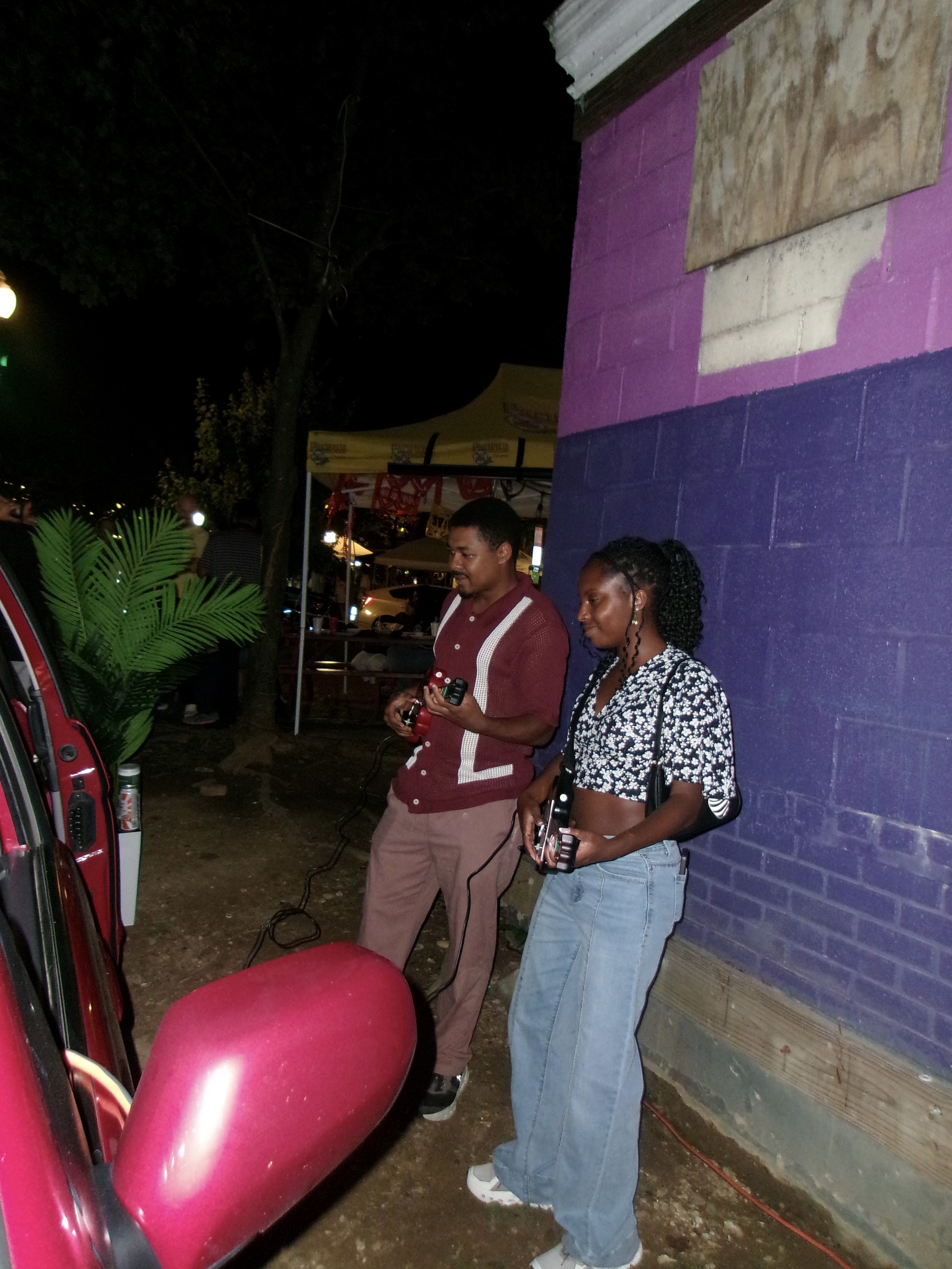 Two people playing Guitar Hero beside the Reset minivan